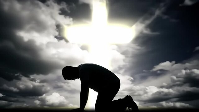A man kneels on one knee with his head bowed in prayer, with a large cross shining brightly behind him against a cloudy sky
