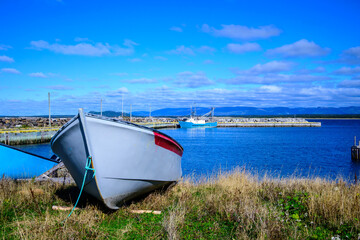 Small commercial harbour in Cow Head, Newfoundland, with fishing boats moored inside a protected breakwater. Calm coastal water and distant hills in Gros Morne National Park during fall.