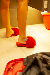Close-up of stylish legs wearing plush red slippers, adding comfort and flair to a casual look. Perfect for home relaxation or a playful aesthetic.