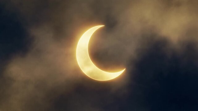 Dramatic Celestial Phenomenon Crescent Sun During a Partial Solar Eclipse Veiled by Atmospheric Cloud Layers in the Daytime Sky