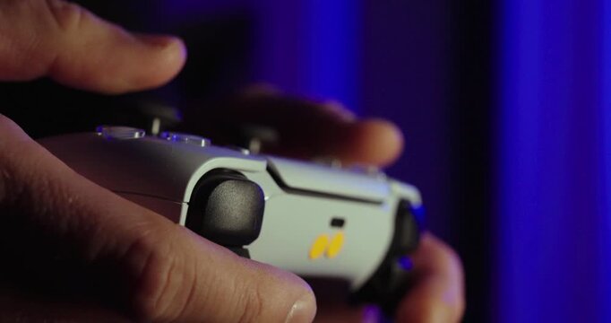 Close-up shot of hands holding a modern game controller with cinematic blue ambient lighting, representing gaming, esports, and immersive digital entertainment.