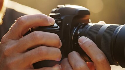 Close-up of a person taking a photograph with a professional digital camera outdoors in the sun