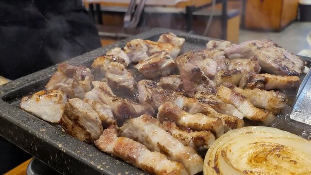 달궈진 석쇠 불판 위에서 노릇하게 익어가는 한국식 삼겹살 구이