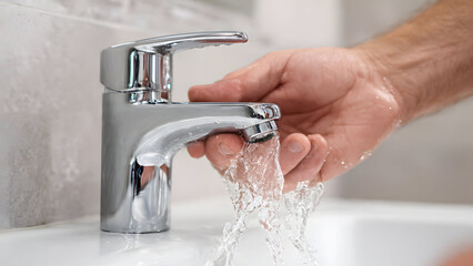 Professional hands carefully installing a modern chrome faucet in a clean bathroom environment