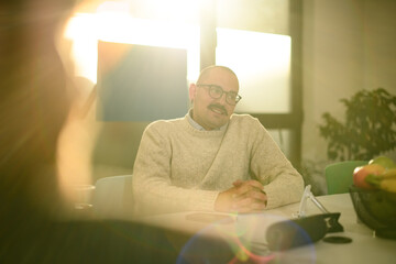 Business discussion takes place in a bright office setting with focused professionals in casual attire during afternoon hours