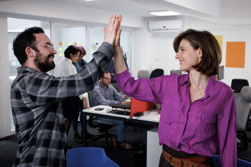 Business professionals collaborating and celebrating success in a modern office environment during the afternoon