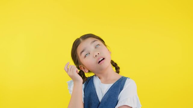 Curious Girl Thinking and Pointing to Head on Yellow Background