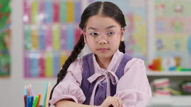 Sleepy Asian schoolgirl waking up bored at classroom desk