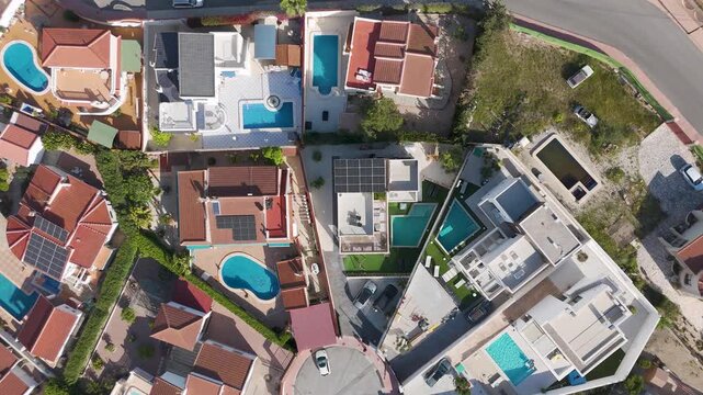 Top down drone view of residential homes with pools and solar panel rooftops