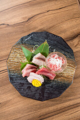 A decorative plate of assorted sashimi including tuna and white fish served with shredded radish and leaf garnish.