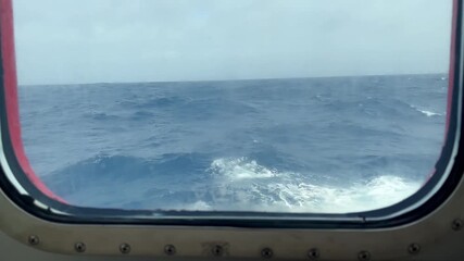 Stormy Drake passage seas seen through passenger ship foggy side window close to water line. Big waves causing ship to list and pitch.