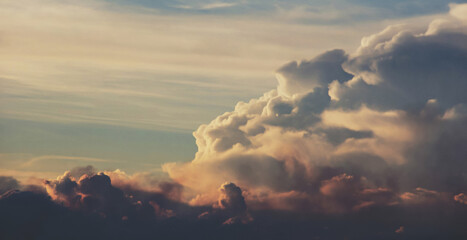 Towering Cumulus Clouds Glowing With Warm Golden And Peach Light Against A Soft Blue Sky, Capturing The Majestic Build Up Of A Summer Storm Over A Calm, Hazy Horizon

