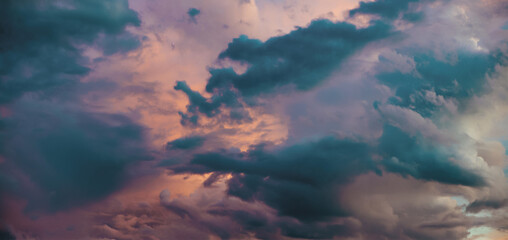 Naklejka premium Moody Twilight Sky Filled With Deep Teal And Indigo Storm Clouds, Tinted By Soft Pink And Purple Highlights From The Setting Sun, Creating A Dramatic And Painterly Evening Cloudscape