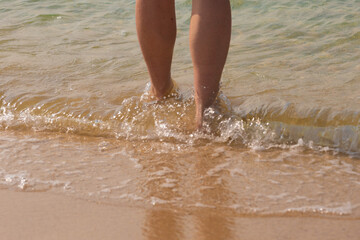 Fototapeta premium Bare feet walk on the sea surf, on water and sand