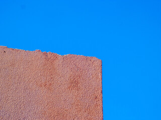 Contrast of textures. Clean, strong lines and colors. Rough wall against the clear blue sky shows the rough against the smooth. The colors stand out.