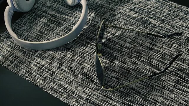 Headphones and glasses placed on a textured black and white table mat with a minimal design