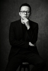 Fototapeta premium Stylish thoughtful asian businessman posing in black suit portrait