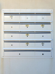 multi unit letterbox mounted against white wall with individually locked compartments for the delivery and collection of mail