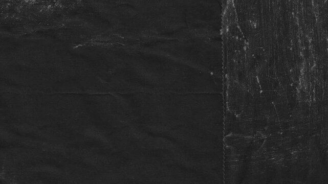 Textured black paper surface with subtle scratches and aged appearance in abstract dark backdrop