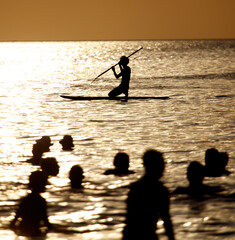 A man is paddling a surfboard in the ocean