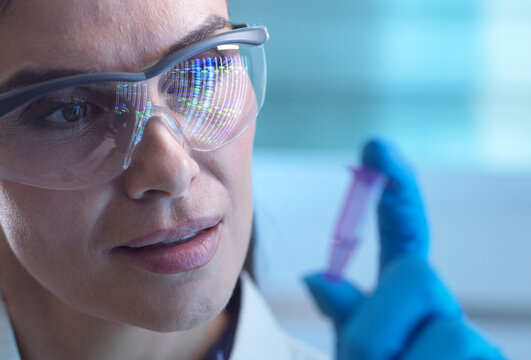 Scientist with safety glasses analysing DNA sample in laboratory