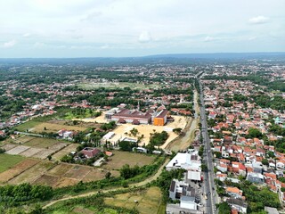 Aerial View of Suburban Residential Area with Green Rice Fields and Main Road in Indonesia