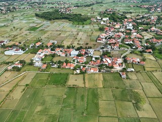 Wide aerial view of suburban town with red roof houses blending into green farmland landscape