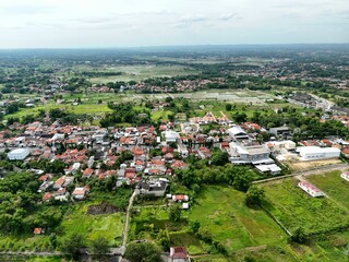 Wide aerial view of suburban town with red roof houses blending into green farmland landscape