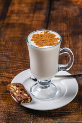 Caffe latte served with cinnamon topping on rustic wooden table