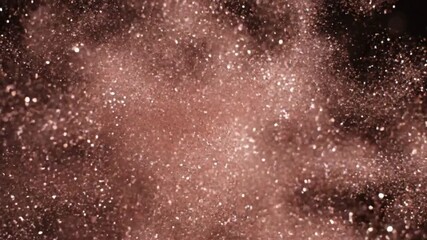 A cloud of shimmering reddish-brown particles suspended in a dark void, creating a sparkling abstract background. - Powered by Adobe