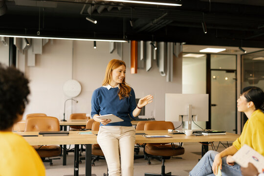 Woman leading a presentation in a modern office setting with colleagues