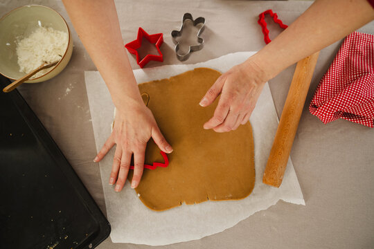 Hands preparing homemade gingerbread cookies for Christmas baking