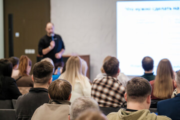 Vibrant conference room scene shows presenter addressing attentive audience during seminar with...