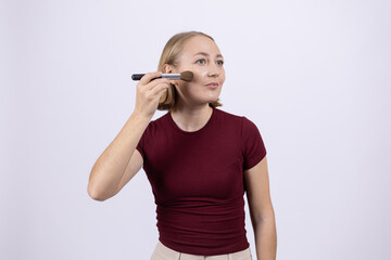 Woman applying makeup to her cheek with a brush