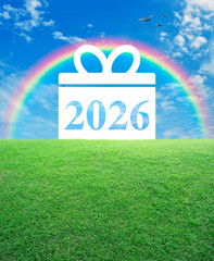 Gift box happy new year 2026 flat icon on green grass field over rainbow, blue sky, white clouds and birds, Business happy new year 2026 shopping concept