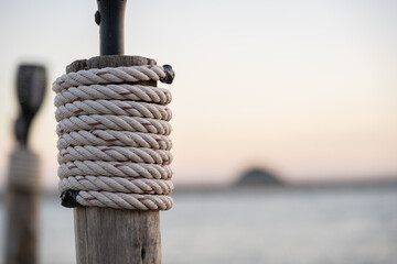Rope Wrapped Around Wooden Post by Calm Sea at Sunset
