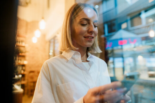 Woman in white shirt using smartphone at cafe with digital workflow