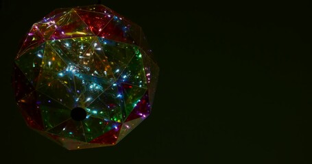 Colorful geometric light fixture glows brightly in dark space. Party celebration background. Dynamic abstract design, slow motion high frame rate. - Powered by Adobe