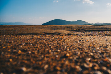 Low-Angle Sandy Beach with Distant Hills Under Clear Blue Sky