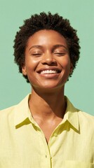Happy African American woman smiling with eyes closed against mint green background