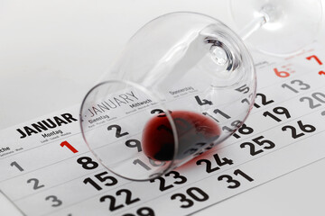 Overturned wine glass with leftover wine on January calendar sheet, concept image for the Dry January Challenge, a New Year's resolution to stop drinking for a month