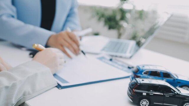 Car Insurance document or lease concept the car broker assisting his customer and explaining the detail of the car contact. Car key Buying or selling signing .