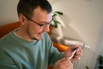 Man smiling enthusiastically while holding a pregnancy test, reacting with happiness and excitement to the positive results, anticipating fatherhood and the arrival of a new family member