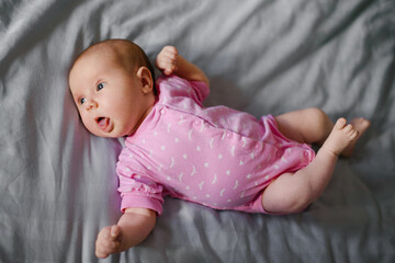 Adorable Newborn Baby In Pink Bodysuit On Grey Bedding