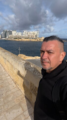 A male tourist in front of the city of Valletta, Malta.