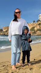Family Girl and boy on winter beach in Golden Bay, Malta.
