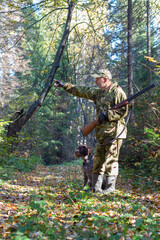 Hunter shows his hunting dog the target in the forest