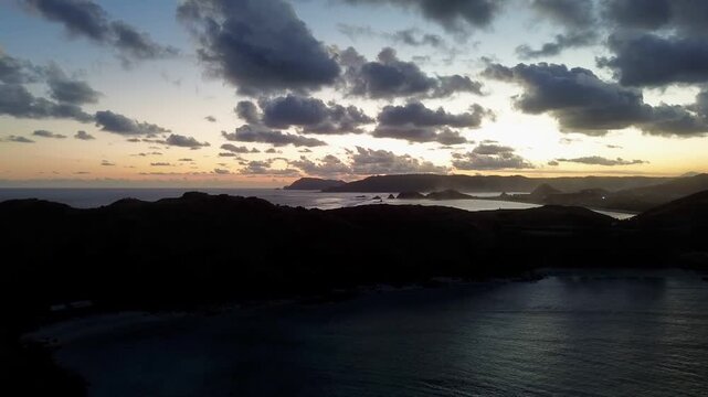 Cinematic drone footage of Tanjung Ann Bay, Indonesia, capturing a scenic tropical coastline and hills glowing at sunset. Suitable for travel films and tourism campaigns.