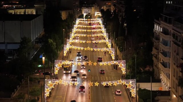 A drone pull-back over the Christmas-lit Vasilisis Sofias, capturing festive lights and traffic flow, ending with a smooth tilt-up revealing the illuminated Acropolis at night.