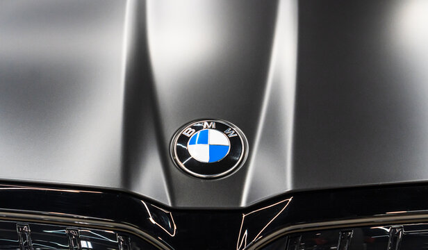 BMW logo on black matte car. Hood and black kidney grille. Emblem of BMW on hood of black car. Black matte BMW 5-Series 540 d G60 logo on car hood. Germany car. 